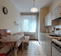 A kitchen in a 2-room apartment with a dining table, light, and a tiled pattern floor.