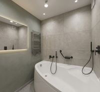 A bathroom in a 3-room apartment with a bathtub, a mirror with lighting, and modern equipment.