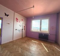 Children's room in a three-room apartment with a wooden decor floor and decorations on the walls.