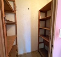 A pantry in a 3-room apartment with shelves for storage.