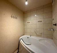 Bathroom with a white bathtub and light tiles in a 3-room apartment.