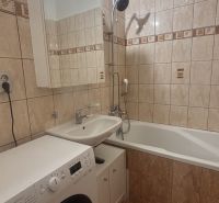 Bathroom in a 3-room apartment with a bathtub, washing machine, and tiled walls.