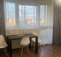 Dining area with a table, white chairs, and a floor with a wooden decor in a 3-room apartment.