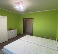 A bedroom in a 3-room apartment with light furniture and green walls.