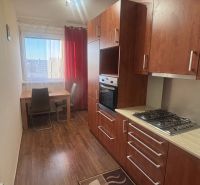 A kitchen in a 3-room apartment with a wooden decor floor and a dining table.