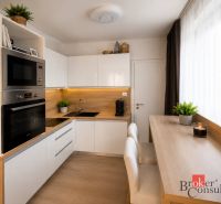 A kitchen in a studio apartment with white cabinets and a wood-patterned floor.