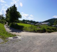Recreational plots in Lysice with a dirt road and green meadows under a blue sky.