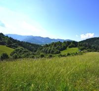 A landscape in Lysice with recreational plots, surrounded by meadows and wooded hills.