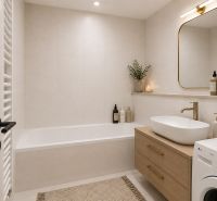 Bathroom with a bathtub, a sink on a wooden cabinet, and a washing machine in a 2-room apartment.