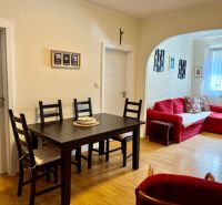Dining area with a red sofa and wooden floor decor in a three-room apartment.
