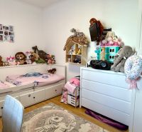 Children's room with a bed, plush toys, and a floor with a wooden decor in a 3-room apartment.