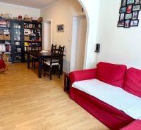 Living room with a red sofa, shelves, a rocking chair, and a wooden-patterned floor.