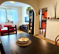 Interior of a 3-room apartment with a living room, kitchen, wooden decor flooring, and a dining table.