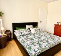 A bedroom in a 3-room apartment with a bed, green details, and a floor with a wooden decor.
