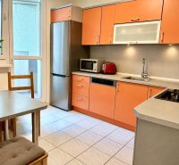 A kitchen in a 3-room apartment with orange cabinets and modern appliances.