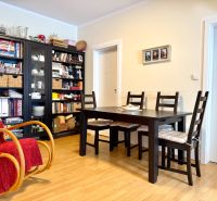 Dining table with chairs, rocking chair, bookshelf, floor with wooden decor.