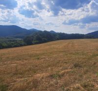 A country with grassy plots for living in Ostrá Lúka, surrounded by forests and mountains.