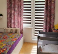 Children's room with curtains and a bed in a 2-room apartment, floor with wood decor.