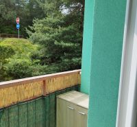 The balcony of a 2-room apartment in Banská Bystrica with a view of trees and a road sign.