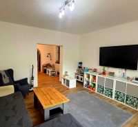 Living room of a family house with a television, carpet, cabinets, and sofas, floor with wooden decor.