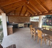 Exterior of a family house in Iža with a wooden shelter, table, and chairs.