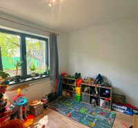 Children's room in a family house with a window and toys, floor with wooden decor.