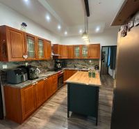 Interior of a family house with a kitchen island, wooden cabinets, and a floor with a wooden decor.