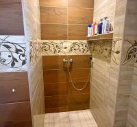 Shower enclosure in a family house with ceramic tiles and decorative pattern.