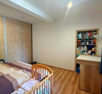 Children's room in a family house with a bed, wardrobes, and a wooden-decor floor.