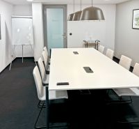 Conference room with a long table, chairs, flipchart, and modern lighting.