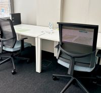 Two office chairs at work desks, black floor with a textile surface.