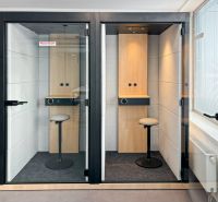 Two telephone booths with wood-decorated floors in offices.
