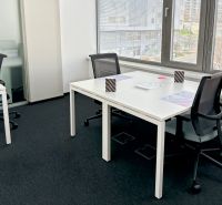 Offices with white desks and black chairs, view from windows with blinds.