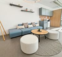 Comfortable office interior seating with a blue sofa, round tables, and hanging shelves.
