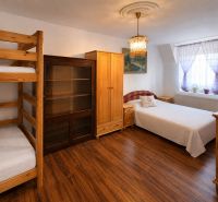 A bedroom with bunk beds, a wardrobe, and a wooden decor floor in a family house.