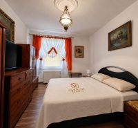 A bedroom in a family house with a bed, wooden furniture, and a floor with a wooden decor.