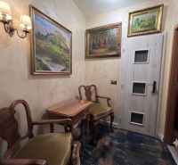 A classic interior of a family house with wooden furniture, paintings, and stylish lighting.