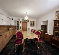 Dining room in a family house with an elegant table, chairs, and a display cabinet with decorations.