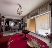 A family house with antique furniture, flowers, and paintings, with a bright space.
