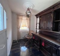 In the family house, you can see an antique wardrobe, a rocking chair, and a decorative chandelier.