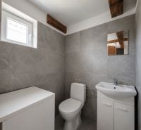 A bathroom in a family house with gray walls, a sink, and a window.