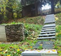 A cabin in Bratislava IV surrounded by a green slope and a staircase made of gray planks.