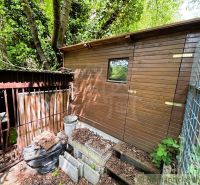 A wooden cottage in Bratislava IV surrounded by a forest and a goose coop.