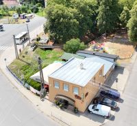 Commercial premises in Divín with a bus stop and surrounding greenery.