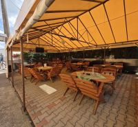 Covered commercial spaces in Divín with wooden tables and chairs on the terrace.