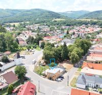 A view of commercial premises in Divín, surrounded by greenery and neighboring buildings.