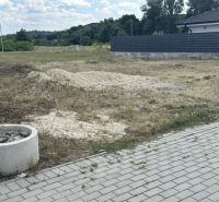 A plot for residential use in Lučenec with a grassy area and a paved walkway on the edge.