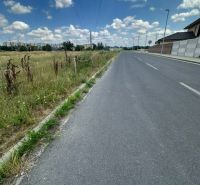 A path near residential plots in Lučenec with a field in the background.