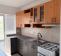 A kitchen in a 2-room apartment with a wooden decor floor and a practical kitchen unit.