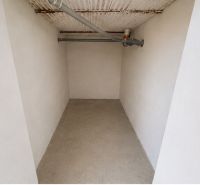 Narrow interior of a cabin with light walls and concrete floor.